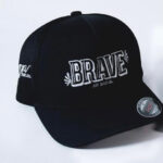 Black flex fit hat, viewed from the front. Text on the front of it reads "BRAVE - Ava Said".